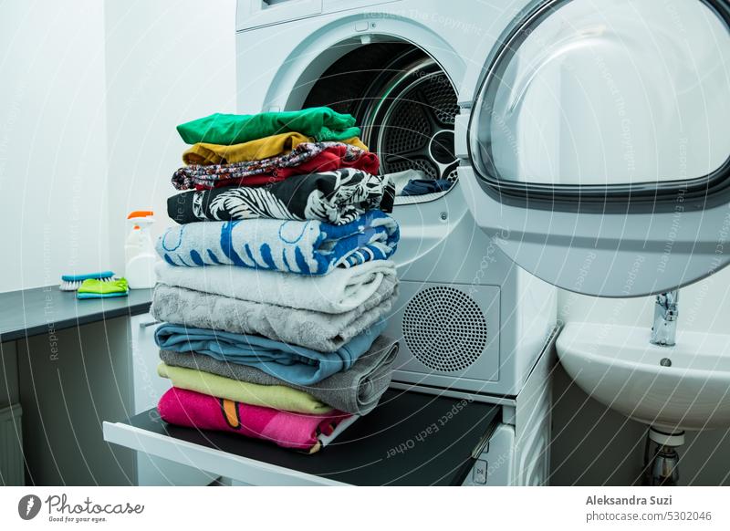 Dryer machine in a Landry room at home drying clothes. Big stack of clean, dry and folded clothes. Household chores concept appliance bathroom casual circle