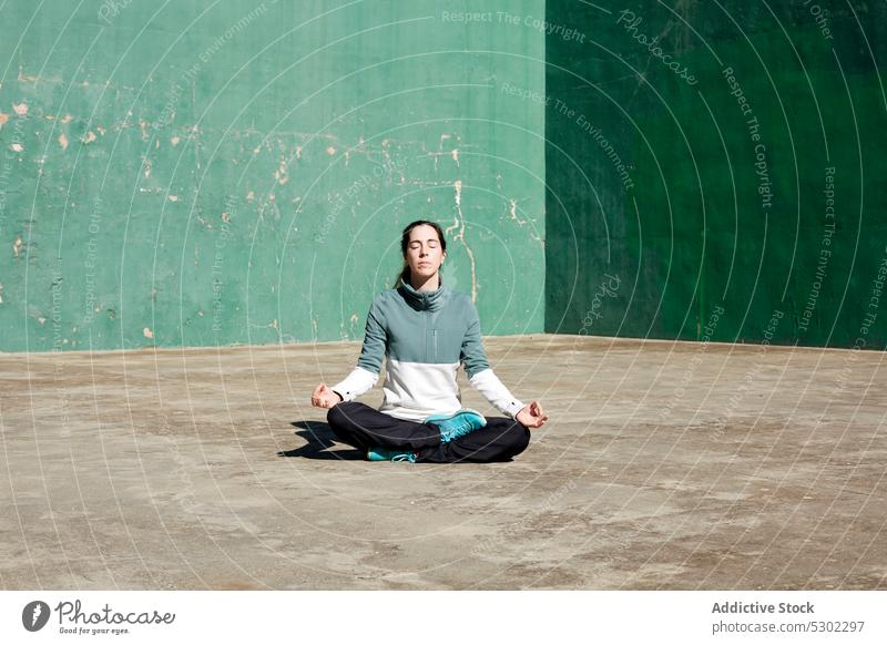 Calm woman in lotus pose yoga meditate mindfulness zen padmasana thoughtful mudra pensive calm female practice young concentrate spirit mental serene concrete