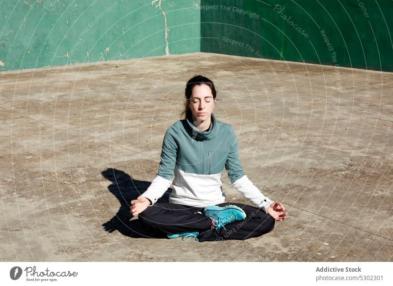 Calm woman in lotus pose yoga meditate mindfulness zen padmasana thoughtful mudra pensive calm female practice young concentrate spirit mental serene concrete