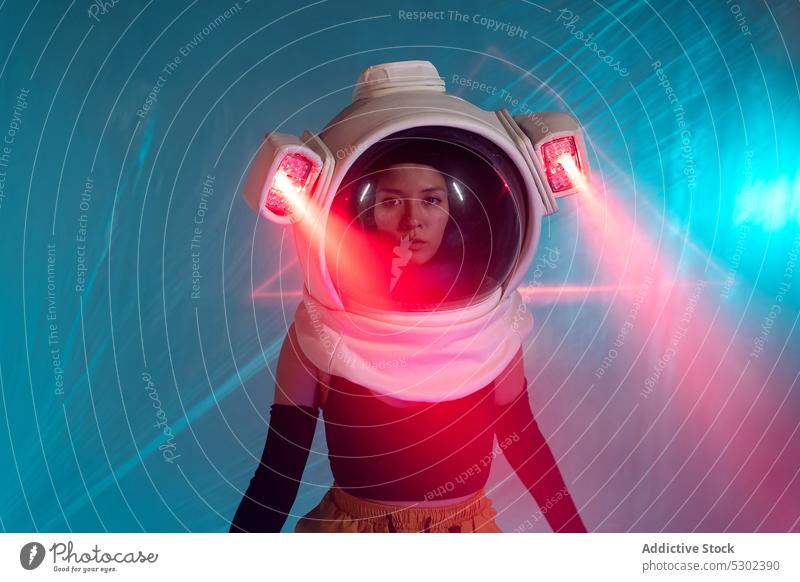 Woman in cosmonaut helmet with neon light woman astronaut model serious confident futuristic portrait appearance style illuminate female glow personality gaze