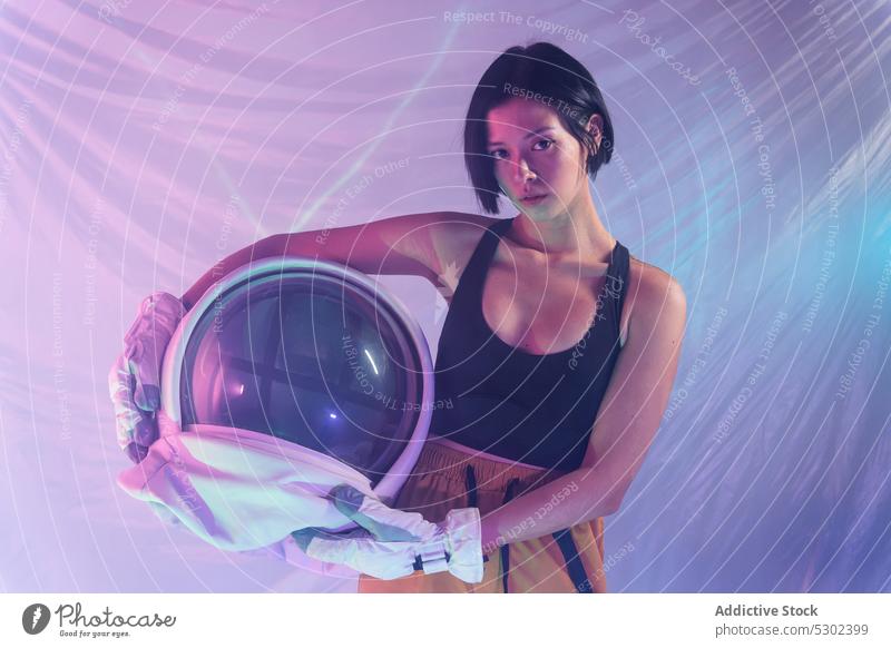 Confident woman with helmet in studio confident portrait serious neon calm protect astronaut cosmonaut futuristic focus thoughtful female young unemotional