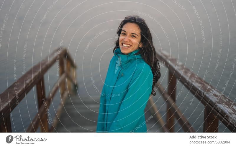 Positive woman on wooden pier near ocean sea admire traveler vacation tourist recreation relax calm female trip casual water nature tranquil railing picturesque