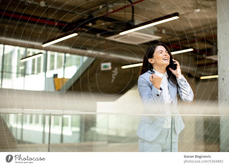 Young business woman using mobile phone in the office hallway caucasian professional businesswoman female people person confident talking cellphone