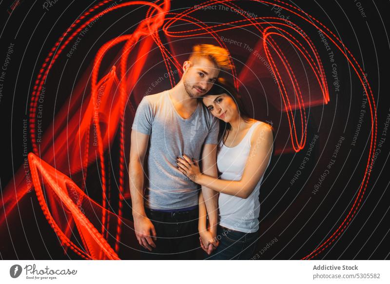 Couple near traces of light couple embraces young man woman casual love relationship together boyfriend trails hugging red bright vivid vibrant girlfriend