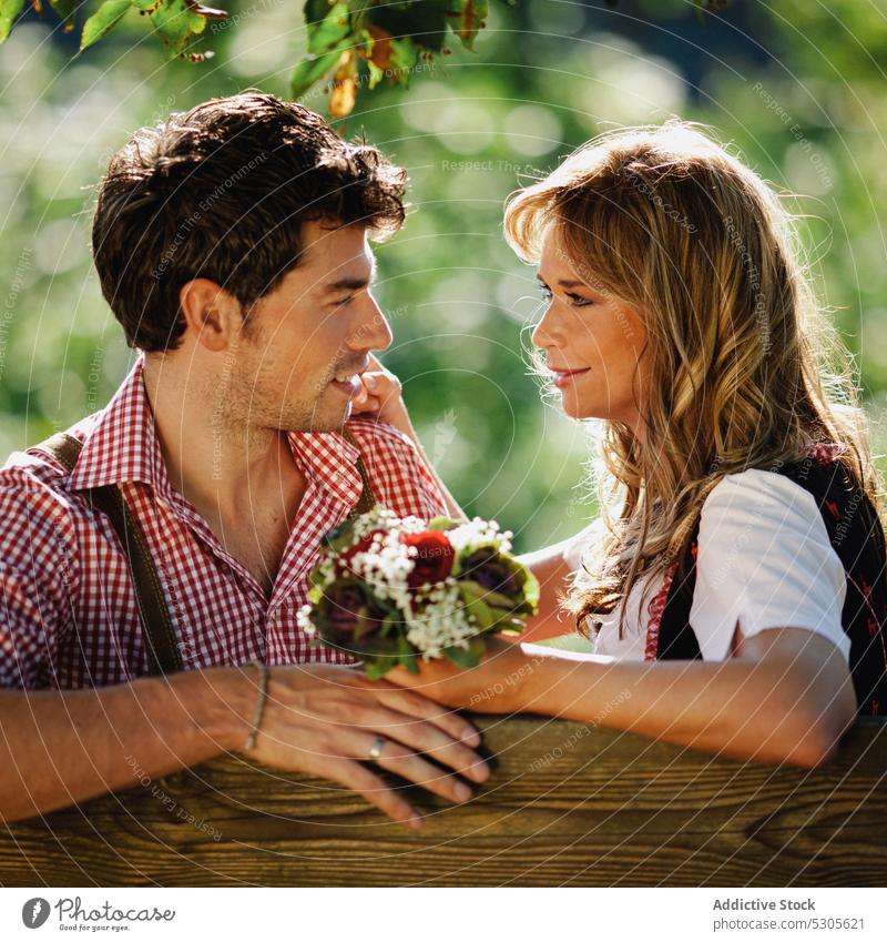 Couple in traditional clothing on bench couple sitting garden austrian smiling sunny daytime man woman park happy lifestyle leisure love costume outfit culture