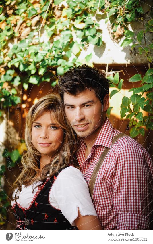 Couple in traditional clothes near fence couple garden austrian clothing sunny daytime man woman park happy lifestyle rustic countryside smiling leisure love