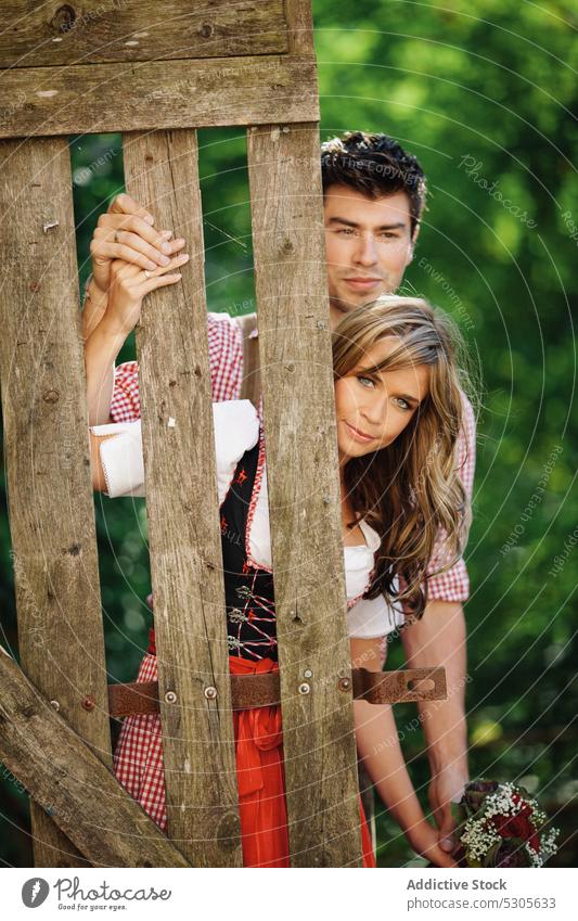 Couple in traditional clothes near fence couple garden austrian clothing sunny daytime man woman park happy lifestyle rustic countryside smiling leisure love