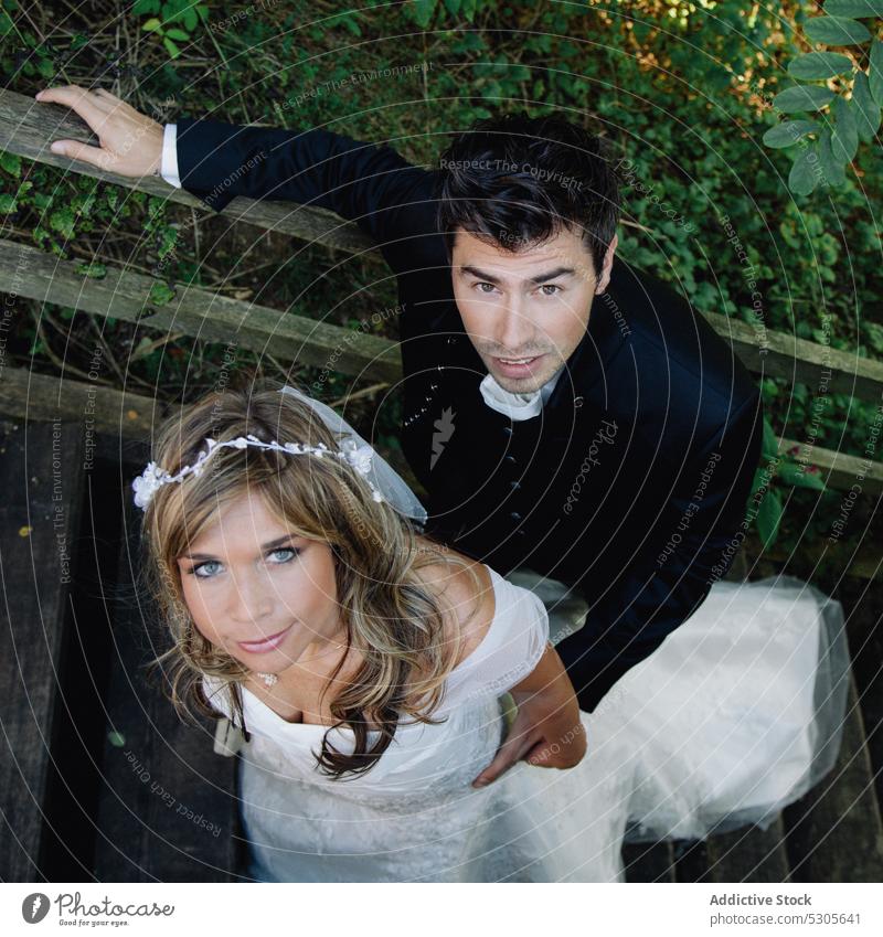 Bride and groom standing on wooden steps couple wedding countryside smiling bride love embracing romantic elegant dress suit woman cheerful relationship