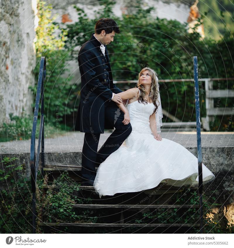 Married couple on stairs near old building wedding steps looking at each other smiling bride groom love embracing romantic elegant aged ancient standing sitting