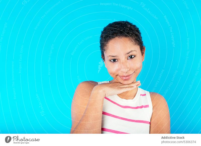 Ethnic woman with short hair touching chin touch chin hand under chin model curly hair stripe top studio shot gorgeous positive smile female ethnic young casual