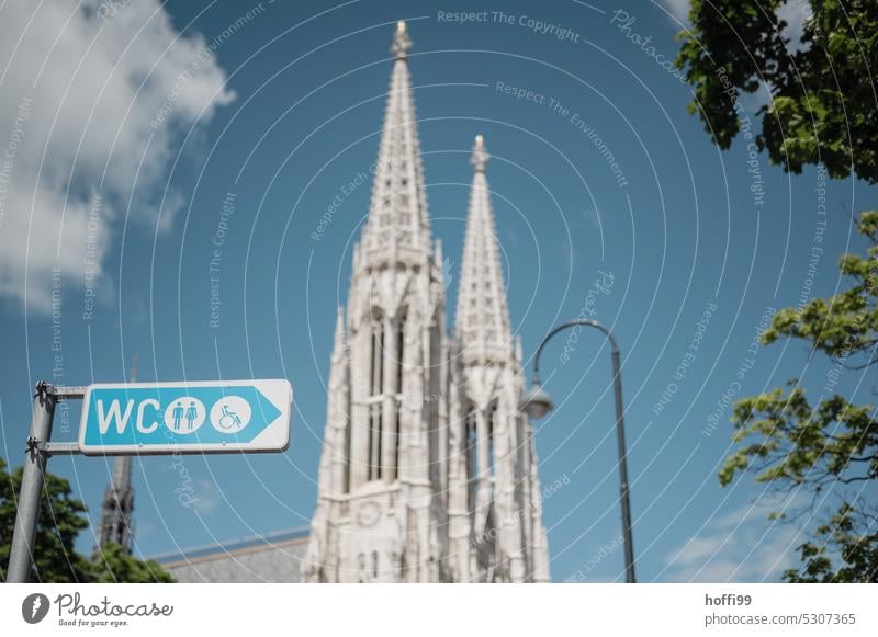 Signpost to the toilet in front of church towers and arc lamp in summer fair weather in the park Road marking LAVATORY Public restroom Sanitary Church towers