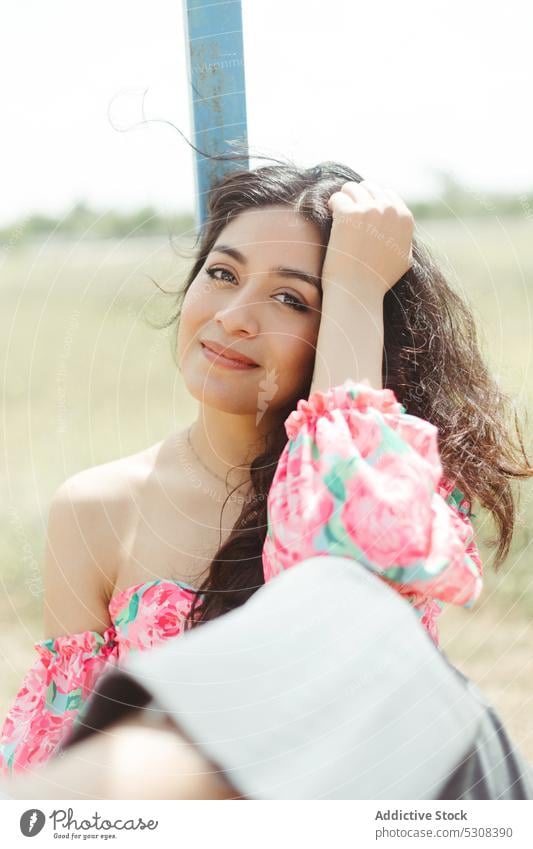 Charming woman standing in shade with blurred background summer smile fence happy nature positive attractive relax sun young female cheerful style sunlight