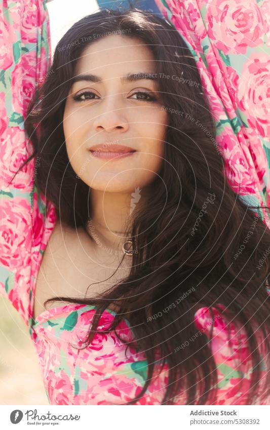 Charming woman standing in shade with blurred background summer smile fence happy nature positive attractive relax sun young female cheerful style sunlight