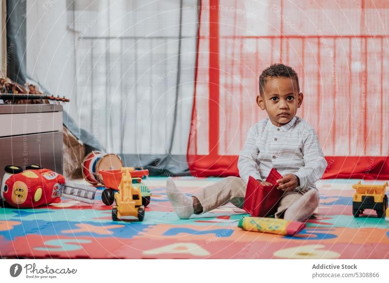 Cute little boy playing with toys toddler relax carpet colorful at home cute adorable child black african american ethnic kid childhood carefree curious