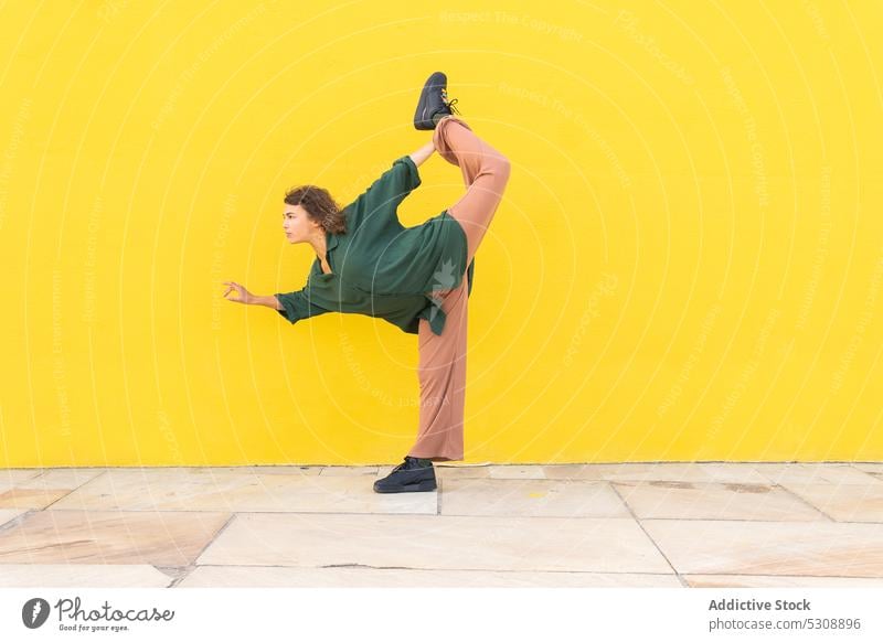 Energetic woman performing yoga pose on street balance practice flexible standing bow mudra zen mindfulness stretch female gesture young calm