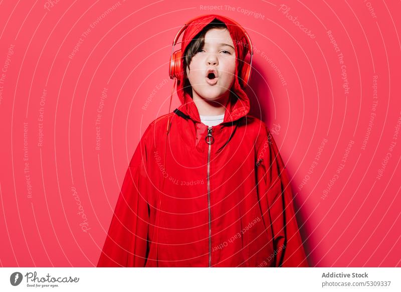 Stylish young girl in red hooded pullover with headphones listen music style trendy casual confident modern child sound sing kid bright color loud song