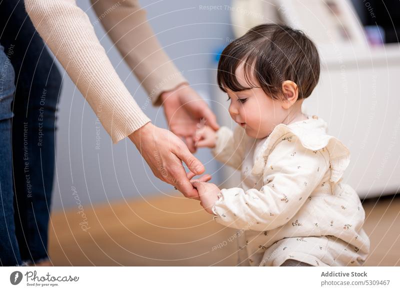 Cute little girl holding hands of mother while walking on floor woman baby step home daughter love together smile parent adorable happy kid child cheerful