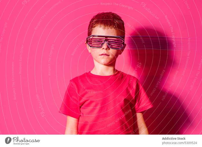 Serious boy in futuristic glasses looking at camera style kid colorful confident bright modern serious child vivid shirt vibrant trendy outfit neon personality