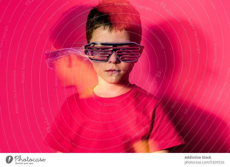 Serious boy in futuristic glasses looking at camera style kid colorful confident bright modern serious child vivid shirt vibrant trendy outfit neon personality