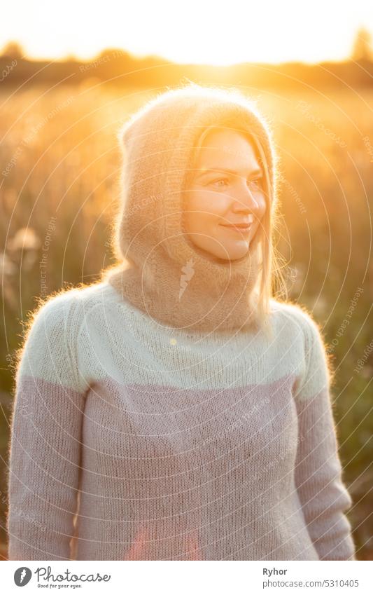 Portrait Of Young Pretty Caucasian Happy Girl Woman In Woolen Jacket Blouse And Brown knitted bonnet Posing In Early Spring Forest In Sunny Day. Enjoy Outdoor Nature. beautiful young woman smiling. power of women. knitted wear, knitted bonnet, knitwear