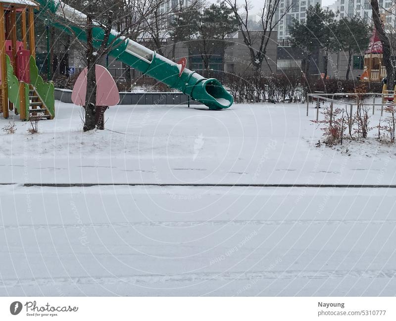 snowy cold winter scene in playground. floor city cityscape white white background snowing Freeze Freezing cold tree outdoor building apartment