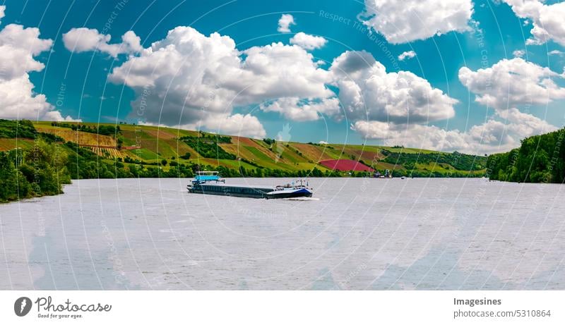 Freighter water transport. Import business and logistics. Cargo ship crossing the Rhine, Rhineland-Palatinate, Germany in Mainz, Nierstein. Vineyards in background