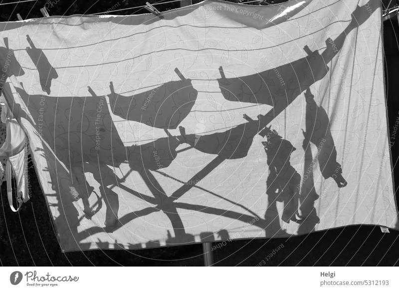 Washing day - on a rotary dryer hangs a tablecloth in the sunlight, on it you can see the shadows of other pieces of laundry, which are clamped down Laundry