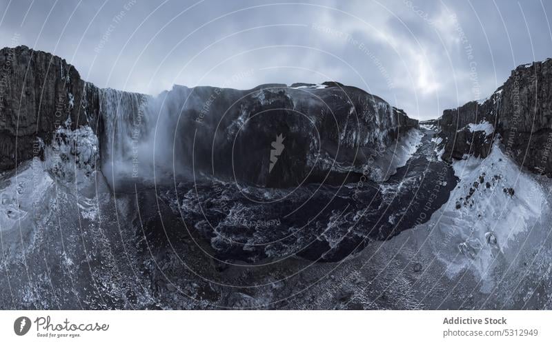 Powerful foaming waterfall falling from slope dettifoss river ice panoramic winter landscape snow nature cliff environment power highland stream cascade flow