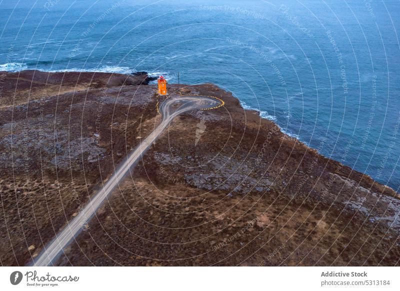 Drone view of road with lighthouse on beach navigate ocean sea nature coast beacon shore water wave splash landscape seashore seaside marine iceland island