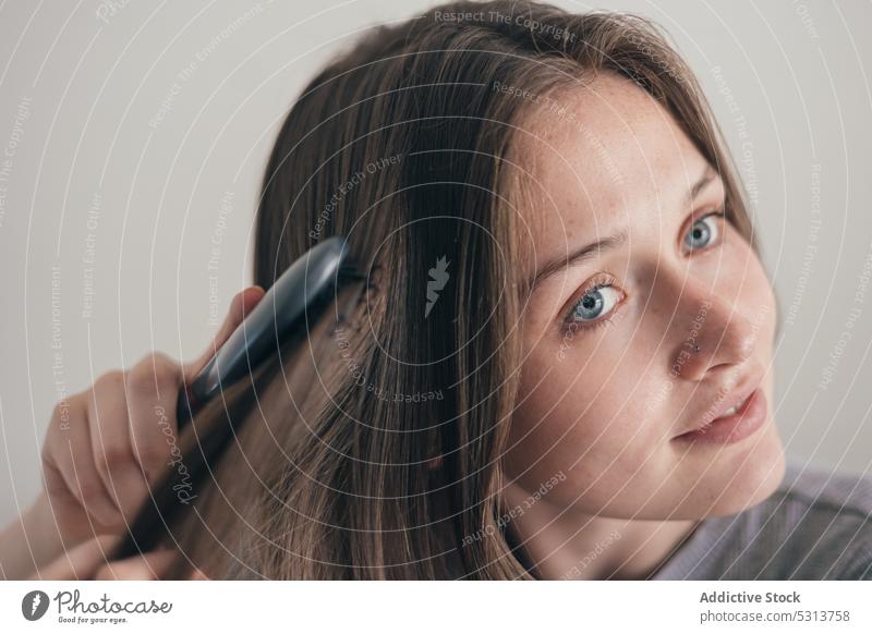 Dreamy woman brushing hair calm tranquil peaceful home young female style serene appearance couch thoughtful daylight daytime sit pensive routine charming