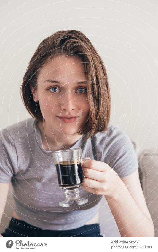 Content woman with cup of coffee on sofa home drink positive breakfast rest young female couch happy casual lounge beverage domestic content delight weekend mug