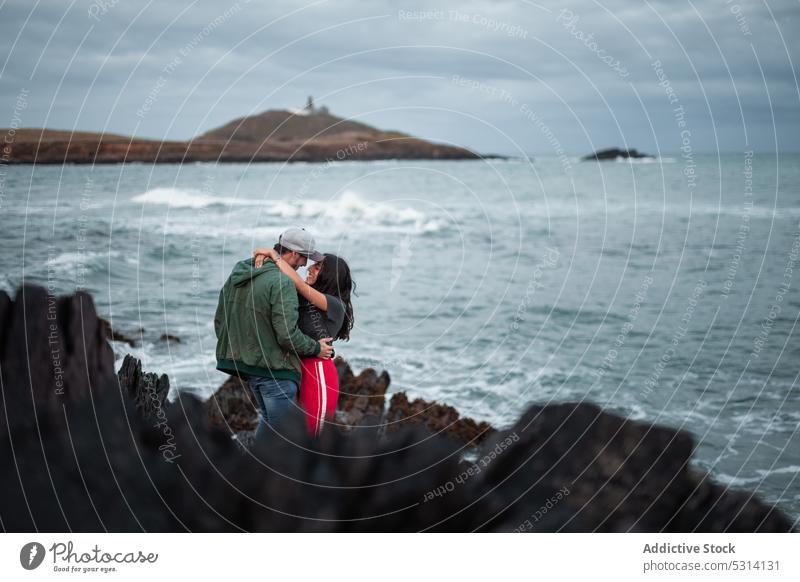 Anonymous couple standing in daylight on seashore relationship cliff travel ocean nature rocky romantic ireland sunset love bonding cloudy cuddle affection