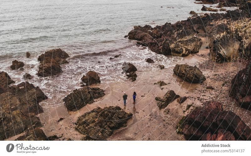 Drone view of unrecognizable traveler standing on rocky seashore people beach ocean seascape tourist cliff sand water ireland picturesque nature coastline