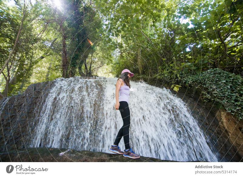 Carefree woman balancing near waterfall in forest hike hiker boulder trunk balance travel nature trip zaragoza spain adventure female traveler smile cascade