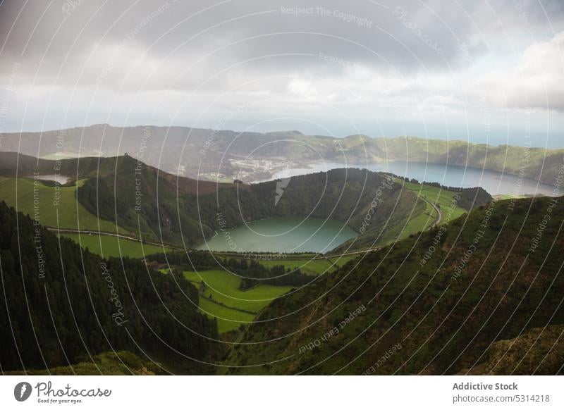 Picturesque view of green valley by mountain ridge with forest and lake road countryside landscape grassland hill terrain field picturesque environment azores