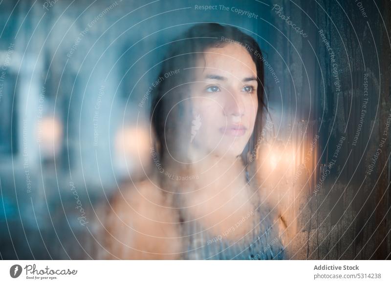 Serious woman looking at window pool reflection transparent glass resort water through glass female enjoy young relax looking away through window glad pleasure