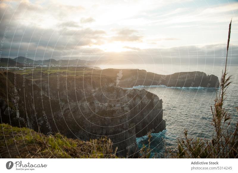 Picturesque view of rocky cliff with settlements near ocean countryside mountain field nature meadow grass sunset valley azores region highland landscape scenic