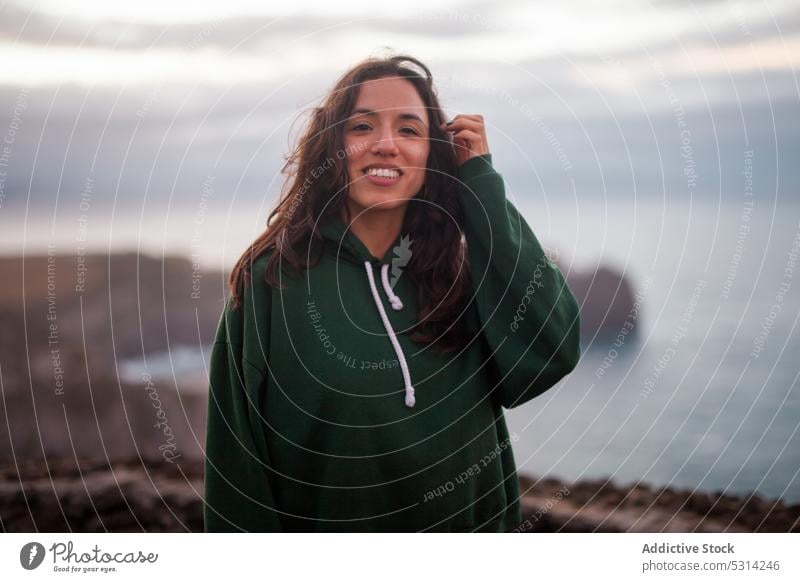 Happy woman looking at camera a cloudy day sea beach coast shore smile happy cheerful young vacation azores portugal seashore water female ocean wave nature