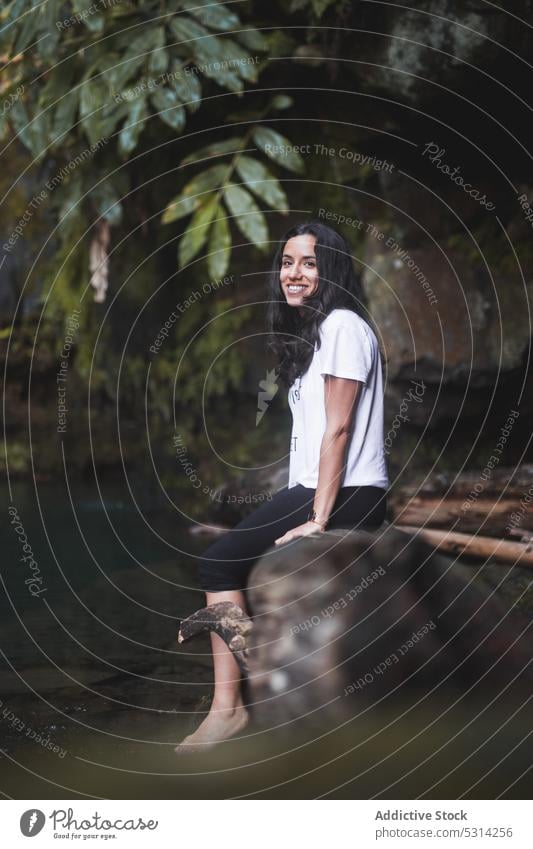 Woman sitting on stone and playing with water woman countryside cliff relax rock summer barefoot azores region edge daytime female traveler weekend lady