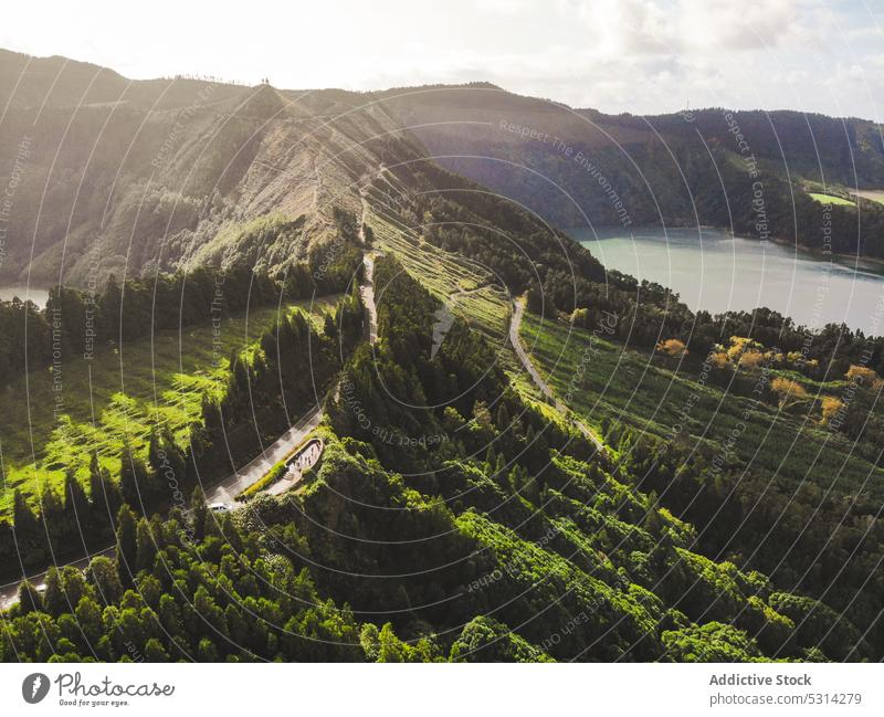 Amazing landscape of mountain ridge with roadway near lake sunlight tree cloudy picturesque countryside azores island portugal europe scenery sunshine