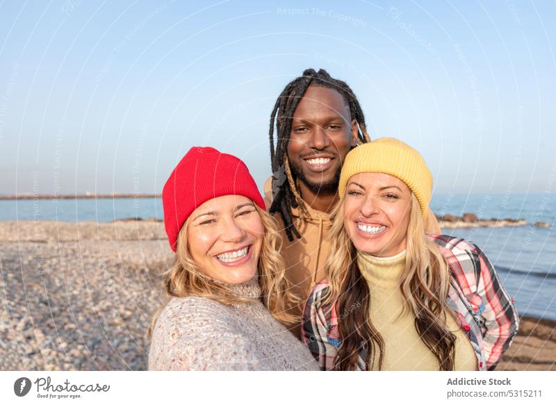 Group of happy diverse friends hugging on beach man women summer sea smile coast spend time multiracial multiethnic african american black cheerful pebble