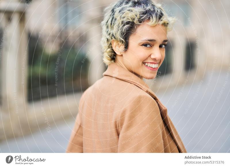 Cheerful woman in stylish outfit walking on pavement smile building street historic style city positive female blond trendy young architecture happy cheerful