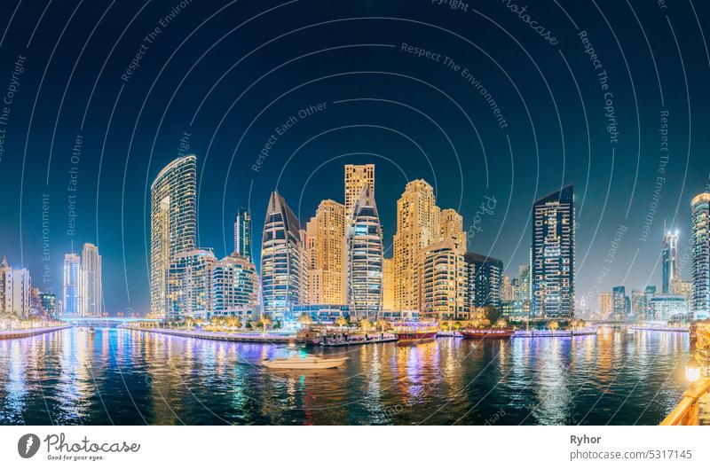 Beautiful Night view of high-rise buildings of residential district in Dubai Marina And Tourist Boat, Sightseeing Boat Sailing On Dubai Marina. Panorama, Panoramic View