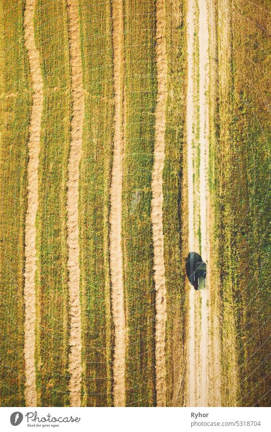 Elevated Aerial View Of Green Car Vehicle Automobile On Countryside Country Road Through Green Fields. Agricultural Country Rural Landscape. Car Drive In Motion. Hay Straw Field Landscape