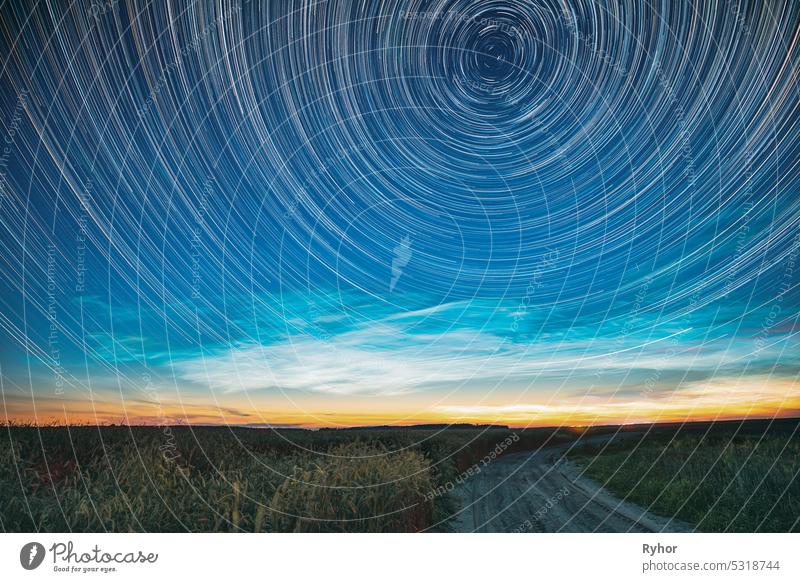 Morning Sunrise In Countryside. Unusual Amazing Effect Of Cloud And Stars Trails Above Countryside Rural Field Landscape With Young Green Wheat Sprouts In Springtime. Soft Colors