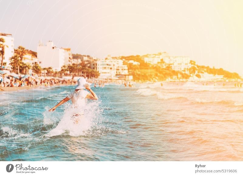 Active Caucasian Young Woman Goes Towards In Sea Ocean. Happy Seaside Vacation. Beach Vacation Concept. Happy Beautiful Girl On Beach Vacation. Young, Pretty Lady Relaxing In Vacation. Bright Summer