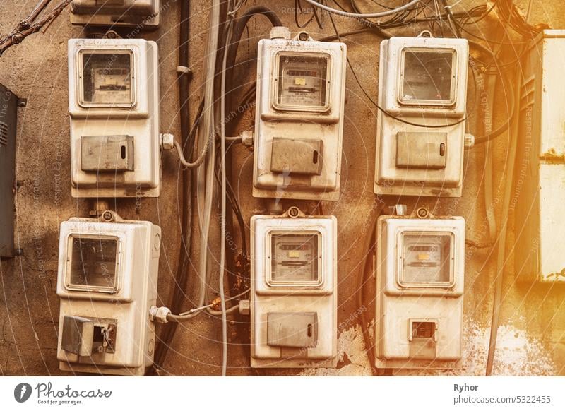 Various Electric Meters Stand A Row. Energy Consumption Concept. Impact On Environment. Dial Electric Power Meters Measuring Power Usage. Need For Saving Energy. Electricity Meter Measures Current Consumed. Electrical Equipment