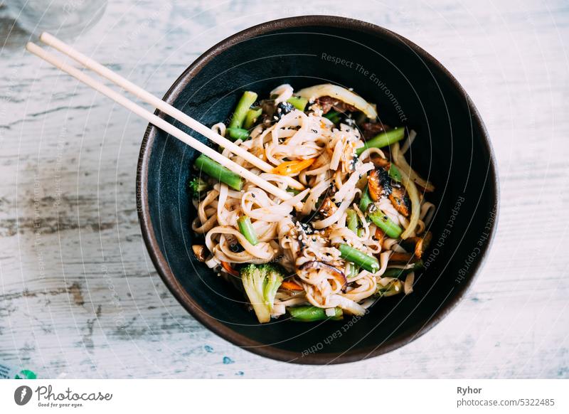 View osf asian noodles udon with pork close-up in a bowl on the table. Flat view black chili chinese chopsticks closeup cooked cooking cuisine delicious dinner