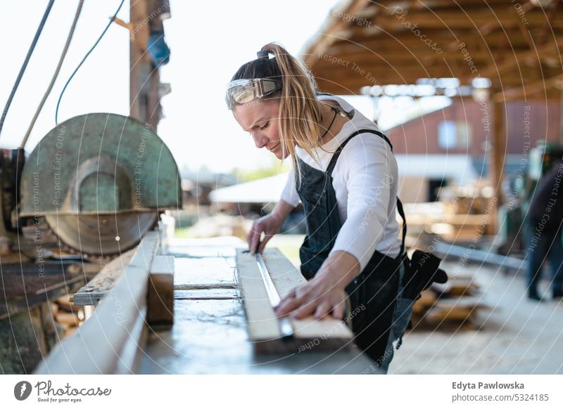 Woman working with wooden planks in a sawmill real people woodshop carpenter entrepreneur expertise craftsperson creativity manufacturing crafts people hobby