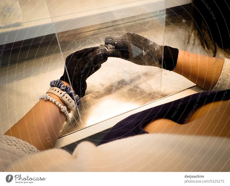 The hearing studio employee wearing black protective gloves grinds on a plastic hearing aid behind a protective glass. Close-up Equipment Profession Hand